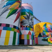 Colorful mural painted on old grain silos featuring geometric patterns and vivid designs, located by the Saginaw River.
