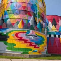 Vibrant, colorful murals painted on old grain silos, featuring geometric shapes and patterns in bright hues, showcasing artistic transformation in Saginaw.